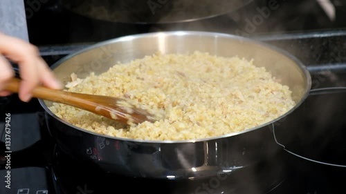 Stirring Steaming Chicken Pilaf in Pot on Electric Stove with Wooden Spoon