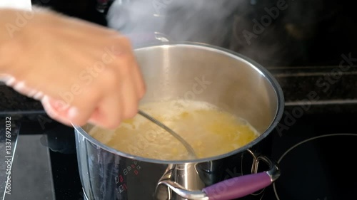 Stirring Boiling Pasta in Pot on Electric Stove with Steaming Water