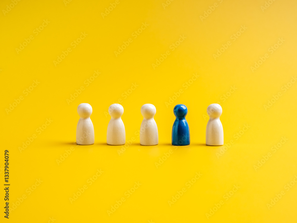 Fototapeta premium The blue one, different standing out of the group of white peg dolls, people symbols, on yellow background. Stand out from the crowd, leadership, unique, influencer, talent people, difference concept.