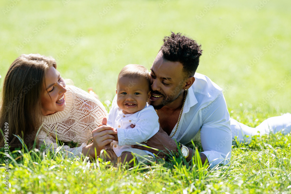 Multiethnic parents and mixed race baby in park. Multiethnic family outdoor portrait. Biracial baby child on yard. Diverse Multiethnic family. Multiethnic father and mother with child lying on grass. Multiethnic parents and mixed race baby in park. Multiethnic family outdoor portrait. Biracial baby child on yard. Diverse Multiethnic family. Multiethnic father and mother with child lying on grass.