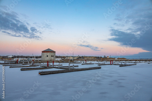 A serene winter scene at Kingston Marina, Ontario, featuring frozen docks under a pastel sky.