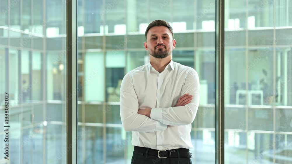 Confident businessman with arms crossed standing in modern office building. Successful male entrepreneur posing in corporate workspace. Confident businessman with arms crossed standing in modern office building. Successful male entrepreneur posing in corporate workspace.
