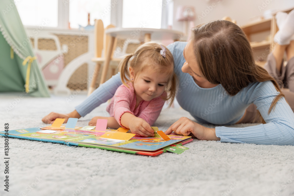 Mother and toddler daughter lying on the floor reading Mother and toddler daughter lying on the floor reading