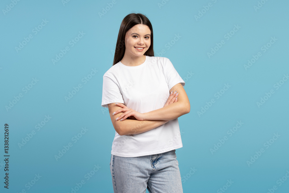 Young girl smiling with crossed arms on blue background Young girl smiling with crossed arms on blue background