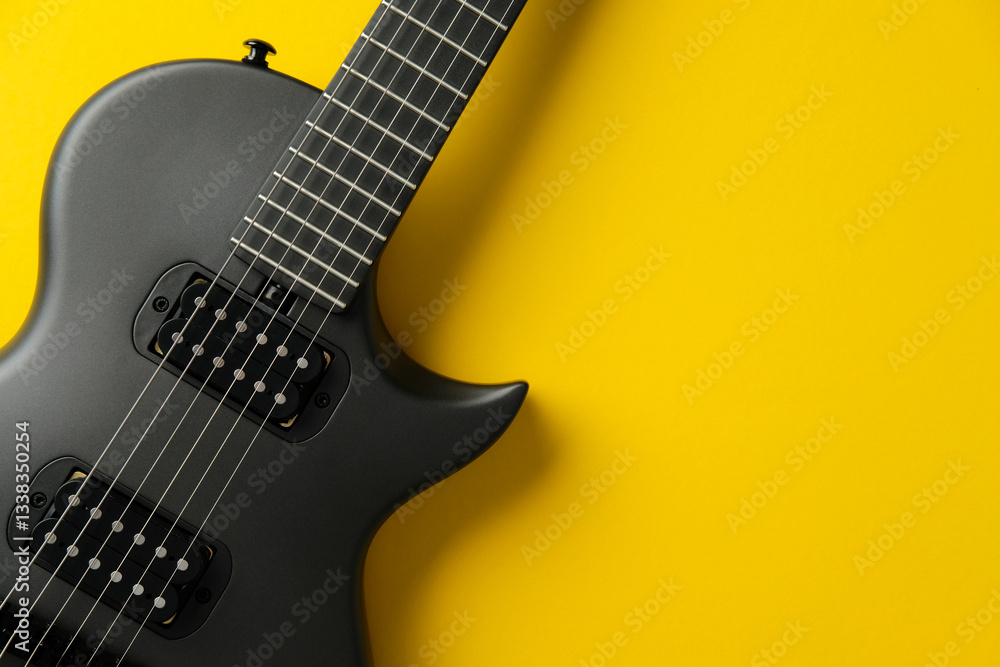 Obraz premium Black electric guitar on a vibrant yellow background. Flat lay, top view.