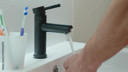 Wallpaper Mural Close-up of man washing hands under running water in bathroom sink with black faucet. Hygiene, cleanliness and self-care morning routine concept Torontodigital.ca