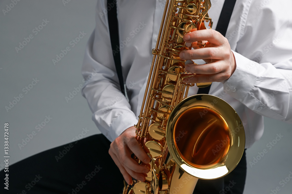 Naklejka premium Professional musician playing saxophone on grey background, closeup