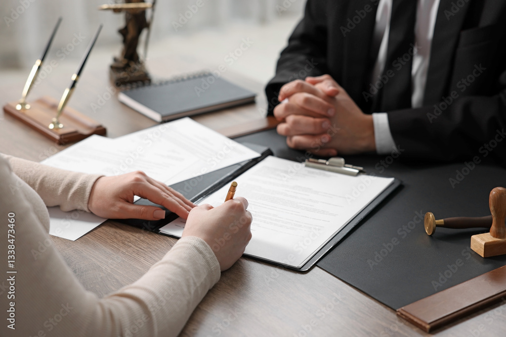 Client signing notarial document during meeting with lawyer at wooden table indoors, closeup Client signing notarial document during meeting with lawyer at wooden table indoors, closeup