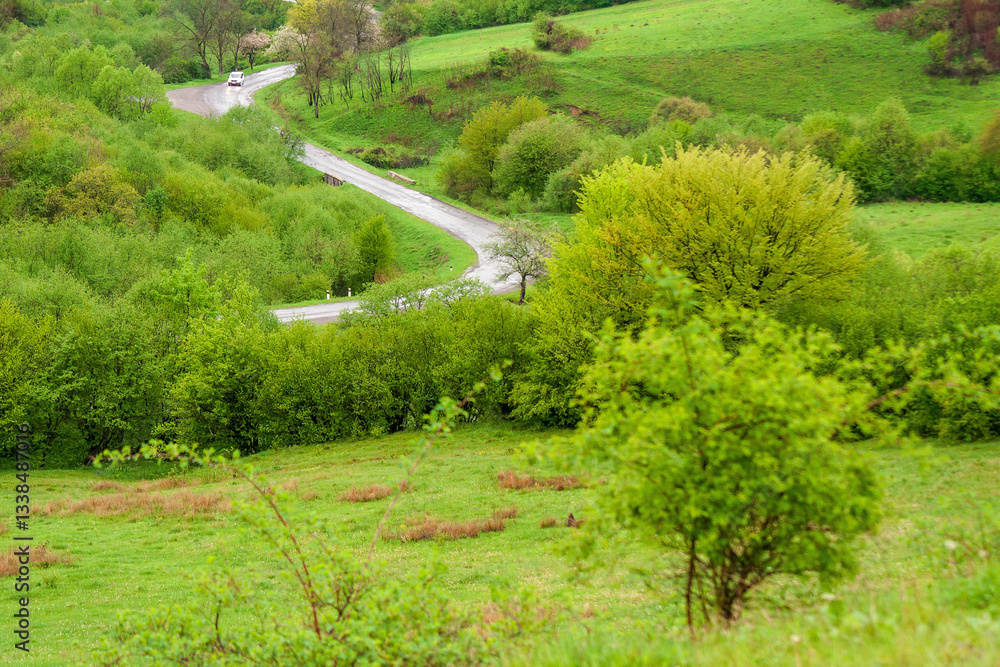 travel landscape, with road through valley. green nature scenery in spring for tourism. beautiful rural background view from the hill with forest. outdoor adventure in the rain