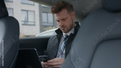 Business man working in the back seat of a car with smartphone