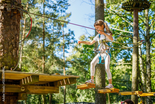 Canvas Print Young girl confidently navigates a challenging rope course high above the ground