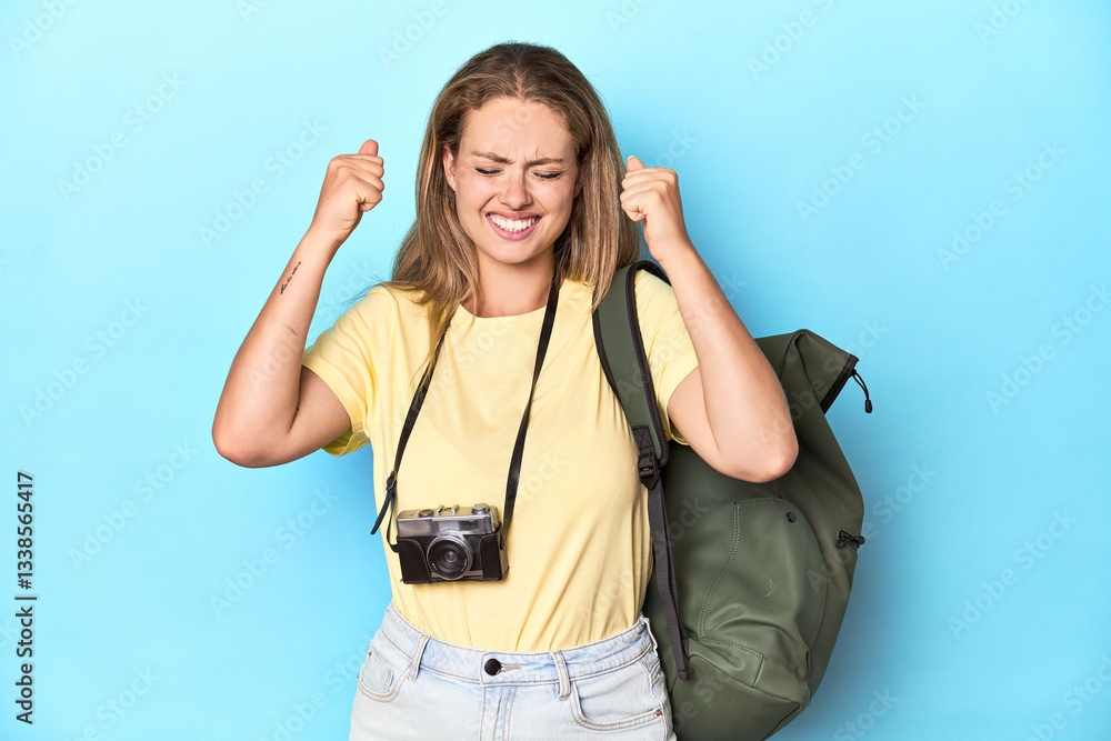 Fototapeta premium Young blonde traveler with camera and backpack in studio covering ears with hands.