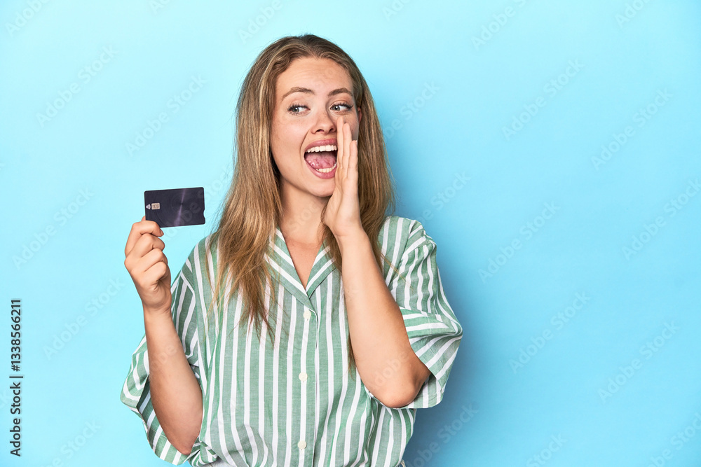 Young blonde with a credit card in blue studio shouting and holding palm near opened mouth. Young blonde with a credit card in blue studio shouting and holding palm near opened mouth.