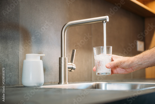 Fotografía Man pouring tap water from kitchen faucet into drinking glass