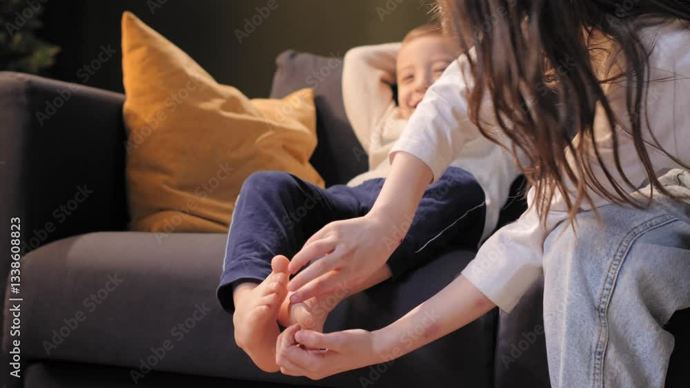 Smiling boy relaxing on sofa while sister massaging his feet Smiling boy relaxing on sofa while sister massaging his feet