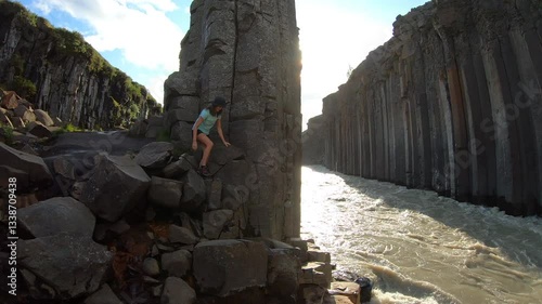 A traveler explores the stunning basalt columns of Stuðlagil Canyon, where Iceland’s unique geological formations rise above a rushing river.