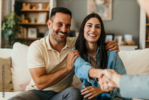 Happy couple shaking hands with financial advisor during meeting at home