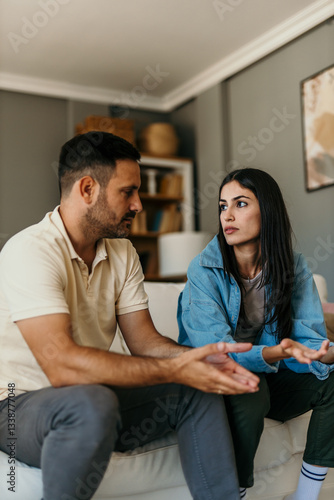 Obraz na płótnie Young couple arguing and gesturing while sitting on sofa at home