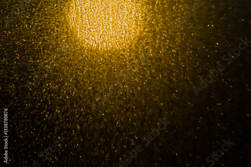 Blurred bokeh light sparkle on golden black background