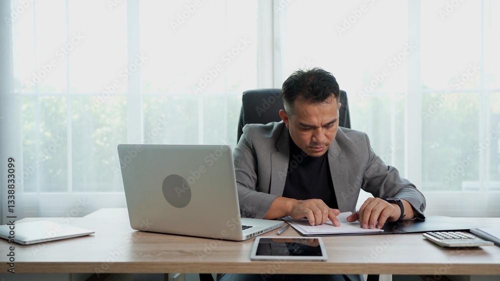Thoughtful Asian Businessman working with document on Desk at office Thoughtful Asian Businessman working with document on Desk at office