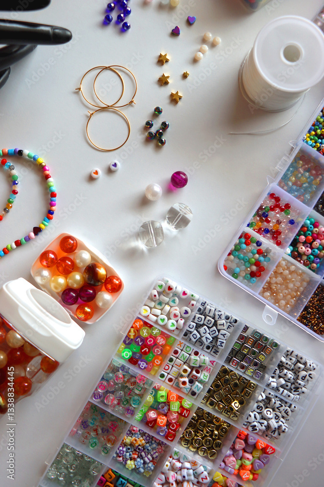 Hand figurine, colorful friendship bracelets, necklaces, various beads and DIY supplies on the table. Making jewelry at home. Flat lay.