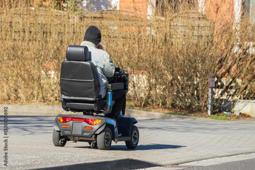 Eine Person in einem elektrischen Rollstuhl auf dem Gehweg unterwegs