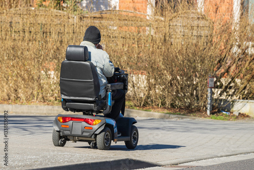 Obraz na płótnie Eine Person in einem elektrischen Rollstuhl auf dem Gehweg unterwegs w salonie