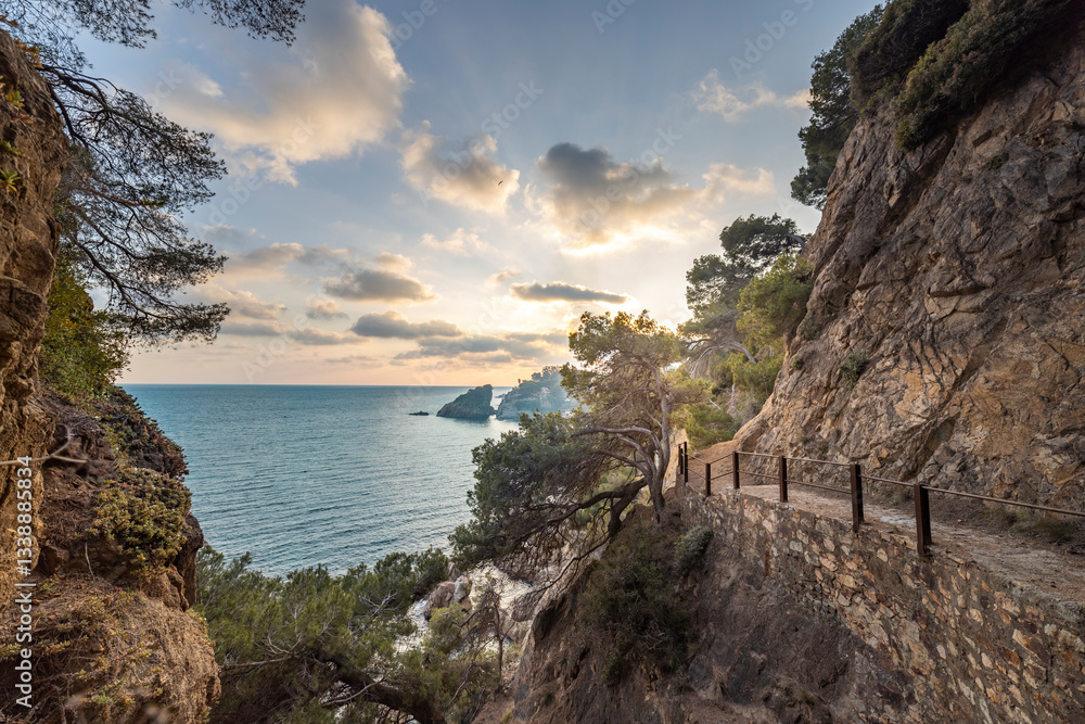 Fototapeta premium A rocky cliff overlooks the ocean with a beautiful sunset in the background