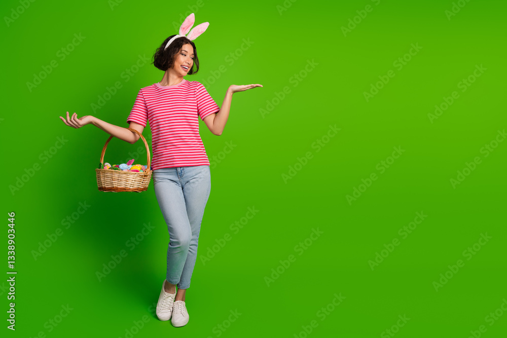 Young woman with bunny ears holding a basket of Easter eggs on a green background, showcasing joy and spring festive spirit Young woman with bunny ears holding a basket of Easter eggs on a green background, showcasing joy and spring festive spirit