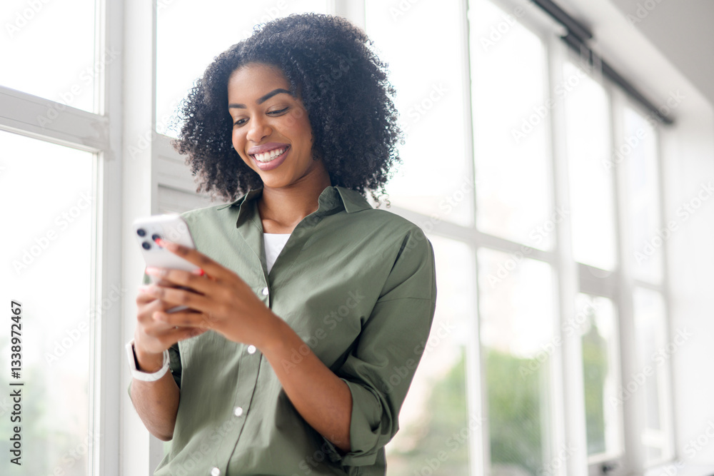 An African-American woman texts on her smartphone, her smile suggesting a delightful exchange with a friend or a loved one, showcasing the joy of digital connectivity. An African-American woman texts on her smartphone, her smile suggesting a delightful exchange with a friend or a loved one, showcasing the joy of digital connectivity.