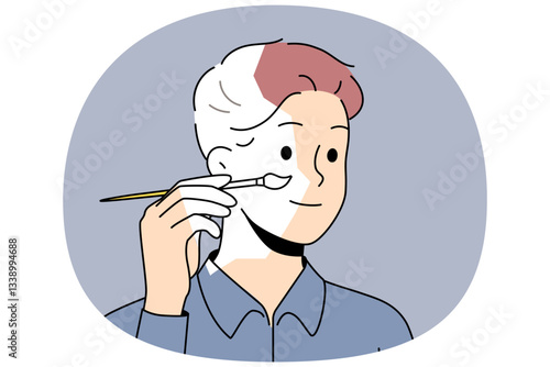 Self-sufficient man artist paints own face and hair with brush, creating self-portrait. Self-sufficient guy draws look, for concept of independence and personal improvements thanks to fortitude