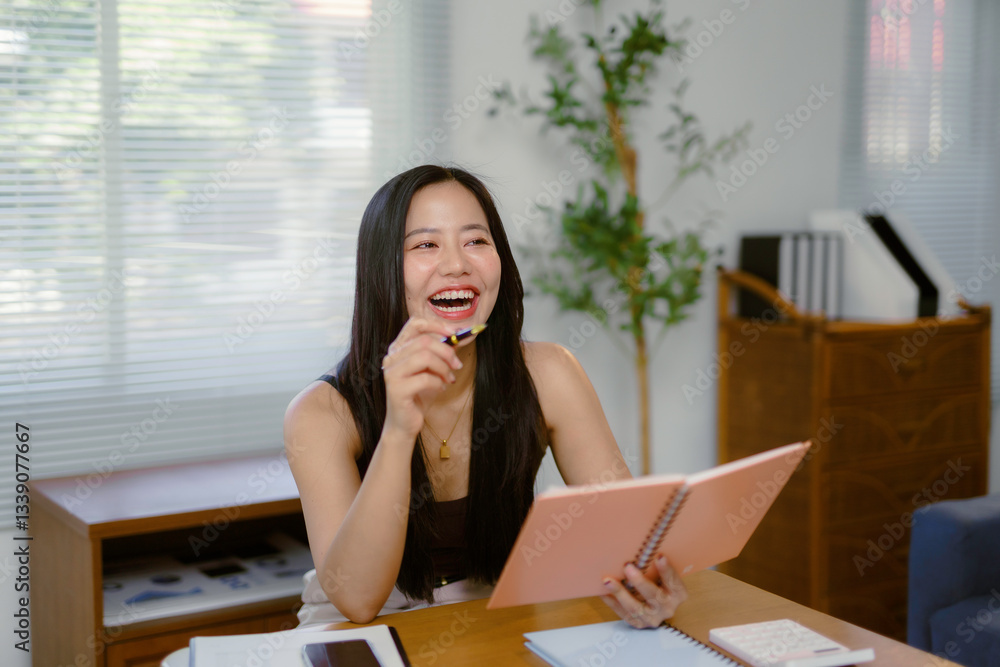 Businesswoman laughing, reading notes, holding pen, working comfortably in bright home office with natural light streaming Businesswoman laughing, reading notes, holding pen, working comfortably in bright home office with natural light streaming