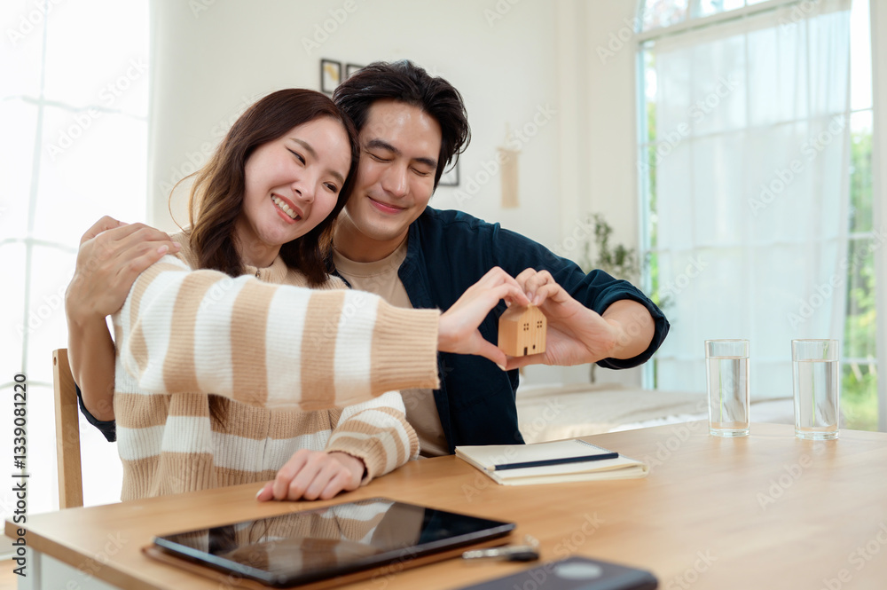 Couple Celebrating New Home Ownership With Miniature House Model in Cozy Living Room Couple Celebrating New Home Ownership With Miniature House Model in Cozy Living Room