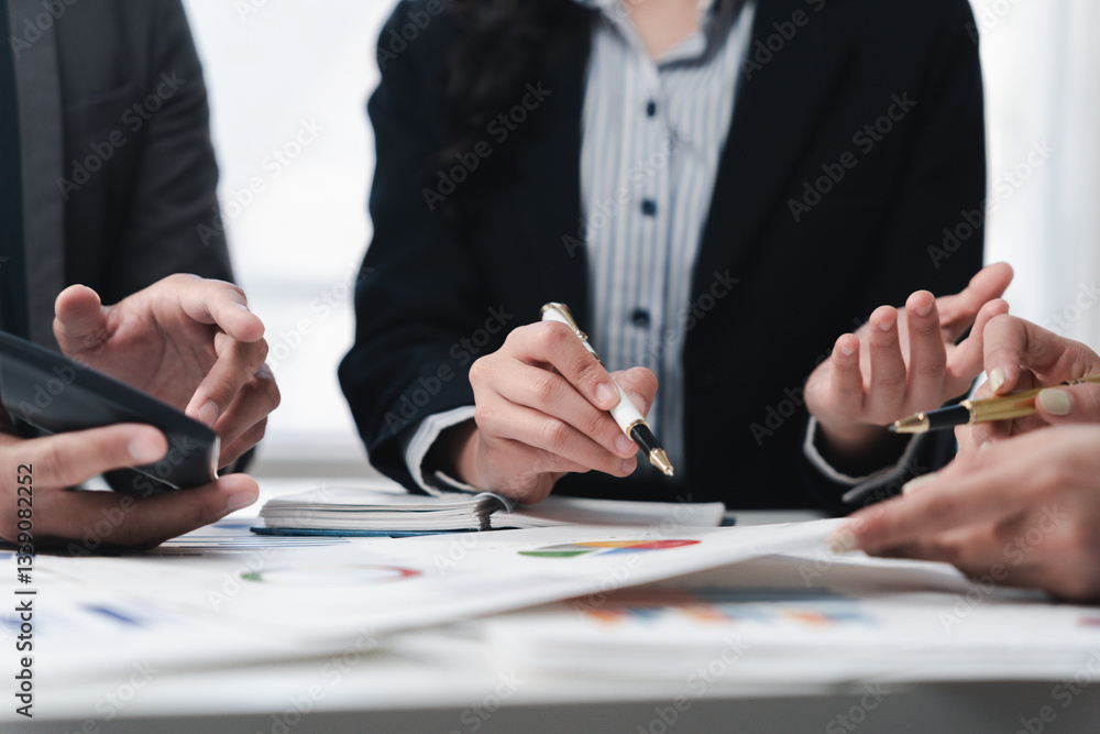 Corporate professionals reviewing financial documents, collaborating intensely around conference table and examining growth metrics Corporate professionals reviewing financial documents, collaborating intensely around conference table and examining growth metrics