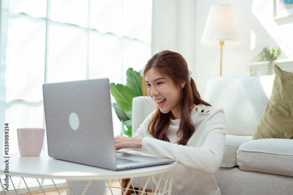 Naklejka premium Young Woman Enjoys Organizing Receipts While Using a Laptop in a Cozy Living Room During Daylight