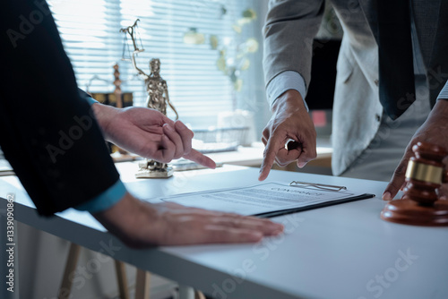 Legal professionals examining contract provisions, law office setting featuring gavel and Themis statuette