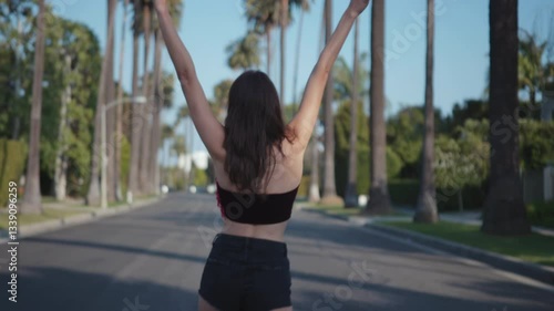 Female fashion model walking down a street in Beverly Hills looking into the camera