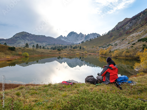 Hiker sitting on the shore of a mountain lake