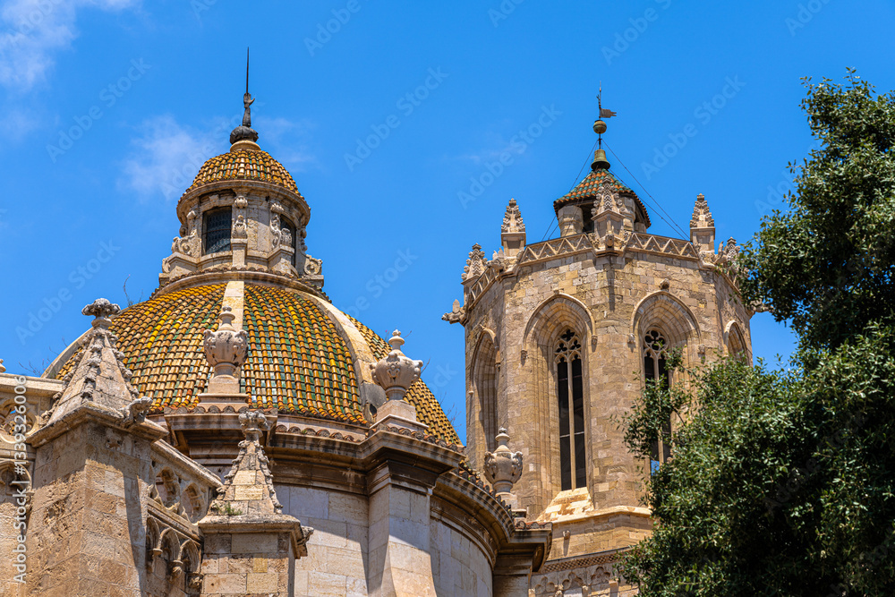 Obraz premium Close view of Tarragona cathedral with colorful roof and clock tower on a sunny day in summer, Tarragona, Catalonia, Spain