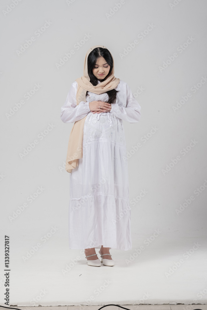 Sick Asian Muslim pregnant woman placing hands on the stomach feeling hungry while fasting. Sick Asian Muslim pregnant woman placing hands on the stomach feeling hungry while fasting.