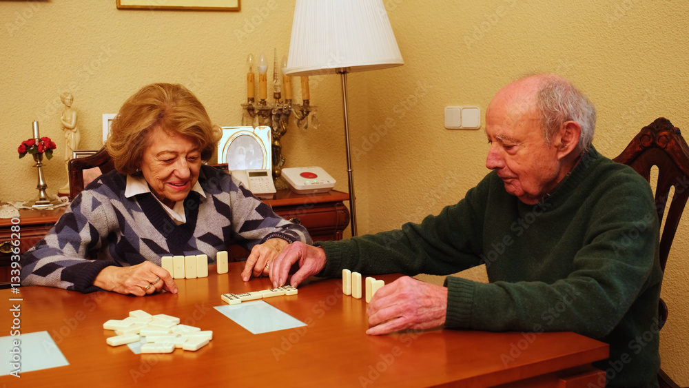 Elderly couple playing dominoes on a wooden table in their living room, enjoying their free time together
