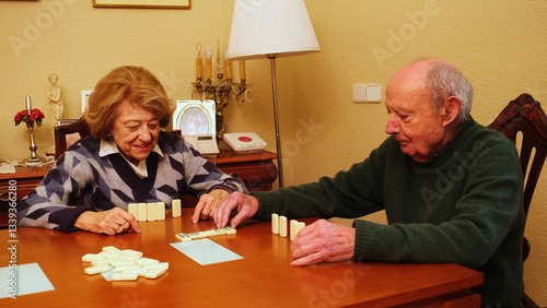 Obraz na płótnie Elderly couple playing dominoes on a wooden table in their living room, enjoying their free time together w salonie