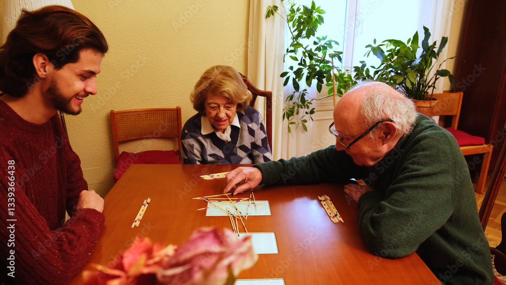 Grandparents and grandson having fun together playing pick up sticks at home