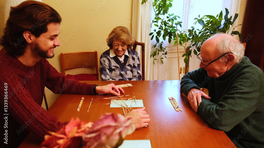 Grandparents and grandson having fun together playing pick up sticks at home