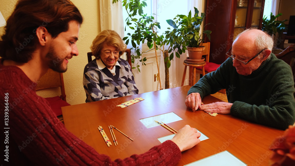 Grandparents and grandson having fun together playing pick up sticks at home