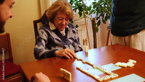 Obraz na płótnie Elderly woman smiling while playing dominoes with her family, enjoying leisure time together w salonie