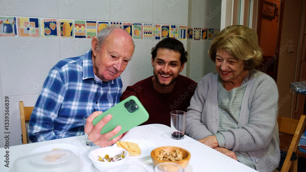 Elderly couple and their grandson enjoying lunch together and using a smartphone