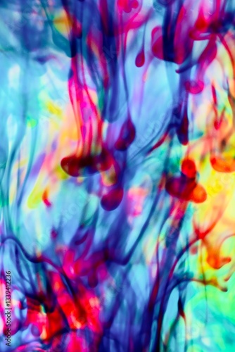 Abstract video with vibrant colors flowing with colored inks dispersed in water. The composition consists of shades of blue, red, green and yellow blending and swirling on a light background, creating