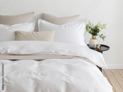 Bedroom with a double bed, fluffy down comforter with a duvet cover, four pillows, one beige cushion and bedside table with vase. Close-up front view vertical photo. Suitable for mockup