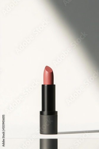 minimalist shot of lipstick standing upright on clean white surface with reflection below